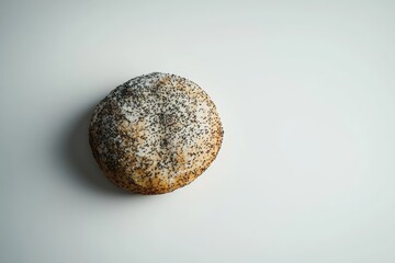 Fototapeta premium A single poppy seed bun, baked golden brown, sits on a white background.