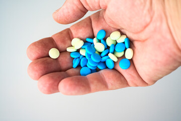 Pills of various colors on the palm of one hand.  White background. Medical devices. Close-up of pills.
