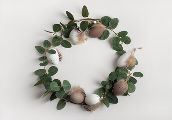 Natural round frame with decorative eggs and branches of eucalyptus. Easter background in earth colours, copy space for your text.