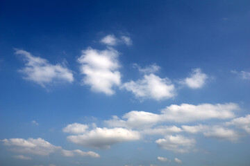 Naklejka premium Bright white clouds drift in a clear blue sky, creating a peaceful, airy atmosphere