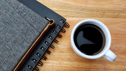 Notebooks, and coffee cup on the wooden desk.