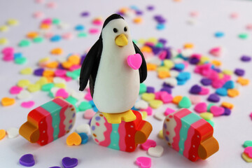 Penguin on colorful ice cream surrounded by hearts