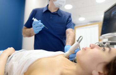 Skillful oncologist puncture of mammary glands of young patient under review ultrasound for...
