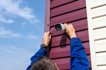 A video surveillance camera in the hands of a technician. Installation of outdoor video...