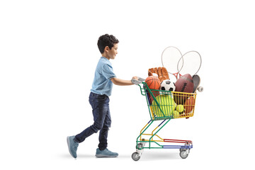 Full length profile shot of a kid walking and pushing a shopping cart sport equipment