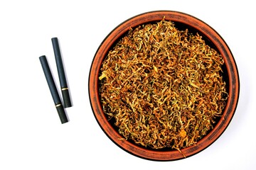 Fermented yellow tobacco in a brown plate on a white background and two cigarettes