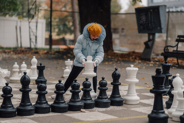 Girl playing giant chess in a park during autumn