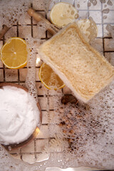Close-up of natural fiber brush, dishwashing foam, lemon wedges, top view