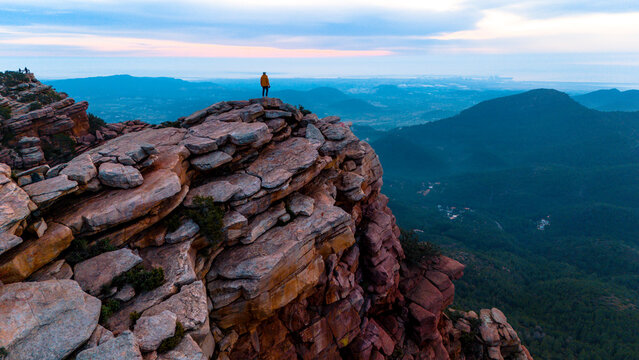 Monta&ntilde;ero de pie en la cima de la monta&ntilde;a observando una vista inspiradora al amanecer