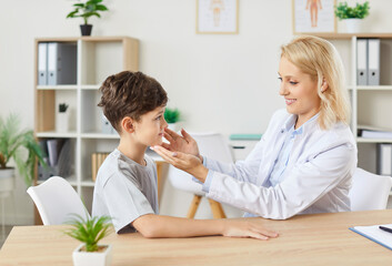 Fototapeta premium Pediatrician, kids doctor examining child talking to little patient, caring woman examining, touching lymph nodes under jaws, checking boy for respiratory infection, virus, flu visit in clinic office