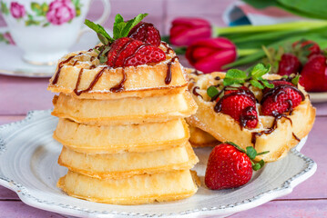 Heart-shaped belgian waffles decorated with fresh strawberries