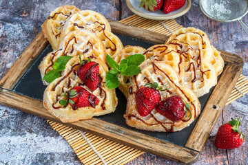 Heart-shaped belgian waffles decorated with fresh strawberries