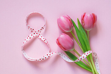 Number eight from a ribbon and a bouquet of tulips on a pink background. Postcard for International Women's Day, March 8