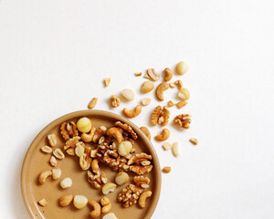 Walnut, macadamia nut, cashew nut on the plate and isolated on beige background. Pile of mixed nuts on the light background.
