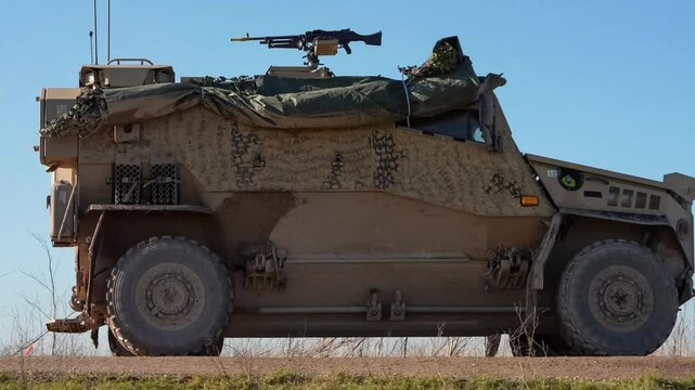 a British army Foxhound four wheeled vehicle moving along a dirt track