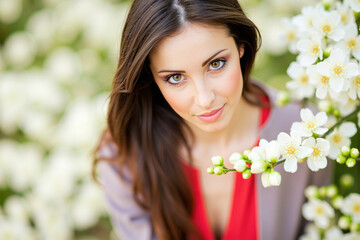 Naklejka premium Beautiful young woman posing near blooming tree in springtime