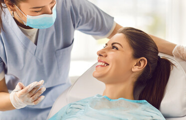Cheerful nurse or doctor orthodontist conducting an oral checkup on a happy female patient using...