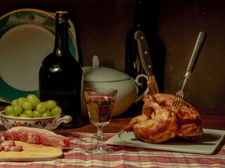 A stylized antique still life with a grilled chicken, a glass of red wine and lard. (rotisserie chicken)	