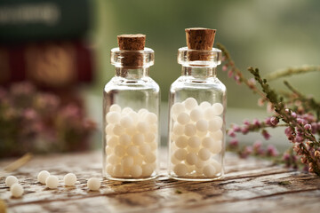 Two bottles of white homeopathic pills or globules with dried herbs and homeopathic books