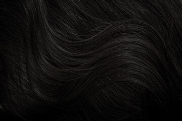 Brunette or black hair. Female long dark hair in black. Beautifully laid curls. Closeup texture in a dark key. Hairdressing, hair care and coloring. Shading gray hair. Background with copy space.