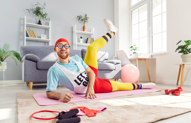 Positive portrait of a funny man stretching during a fitness workout at comfortable home, lying on floor. His exercise routine combines sport and flexibility training in the comfort of home gym.