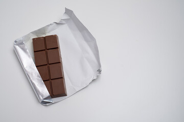 Top view of dark chocolate bar wrapped in foil. Delicious chocolate close-up with nut filling