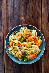 Pasta with seared shrimps, garlic and parsley on wooden table	