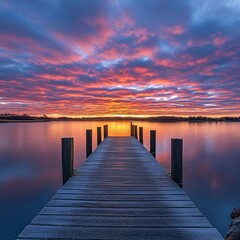 Fototapeta premium Serene sunrise over calm lake, wooden pier leading to vibrant sky, peaceful waters reflecting colors. Use travel, nature