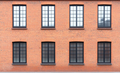 Fototapeta premium The building's facade features a historic brick wall embellished with numerous windows, enhancing its architectural charm and character.