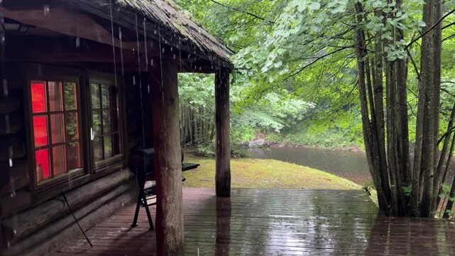 A cabin with a porch and a small lake in the background.
