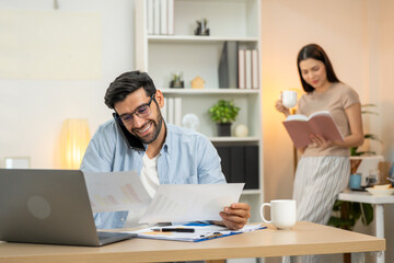 Focused male entrepreneur doing online research over laptop and taking notes while working at home. Portrait of businessman writing in diary while doing online research over computer in home office.