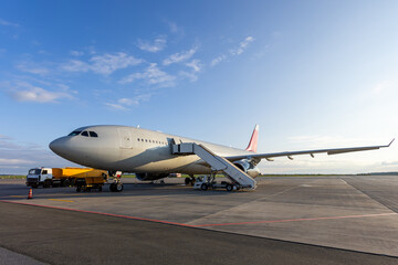 Wide body passenger jetliner with aircraft steps at the airport. Airfield tanker refueling an airplane