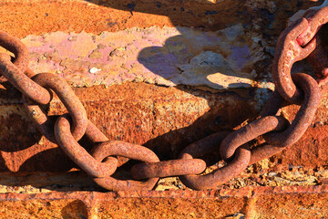 Rusty chain casting shadow on weathered surface