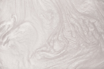 Shimmering silver abstract background. Liquid glitter paint texture waves and swirls. Beautiful shiny white glitter texture. Metallic silver paint close-up as a holiday background.