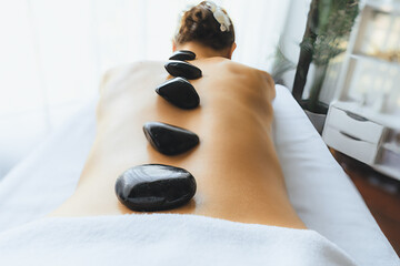Hot stone massage at spa salon in luxury resort with day light serenity ambient, blissful woman...