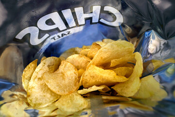 Close-up of the inside of a package of salted potato chips, chips in a bag with text Chips above...