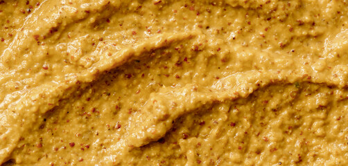 Mustard sauce with grains close-up. Hot spices as a background. Texture of Dijon mustard.