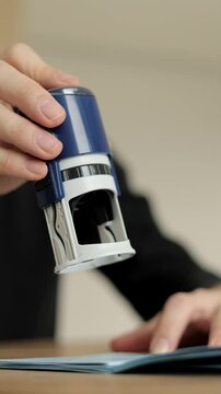 Close-up Of A Man's Hand Stamping With Approved Stamp On Document At Desk. Man Border Control Officer Puts a Stamp in the International Passport. Vertical Video.
