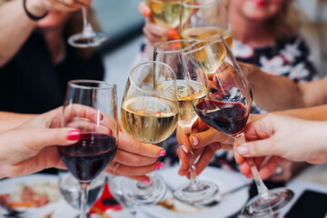 Group of guests celebrate and raise glasses, toasting and cheering with alcohol glasses with wine and champagne in a restaurant on corporate christmas, birthday party prom event or wedding celebration