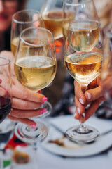 Group of guests celebrate and raise glasses, toasting and cheering with alcohol glasses with wine and champagne in a restaurant on corporate christmas, birthday party prom event or wedding celebration