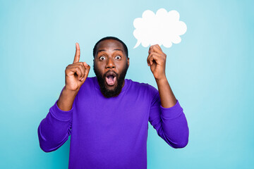 Photo of funny cheerful mixed-race man showing his forefinger up with amazement on face holding white bubble of thoughts isolated vivid blue color background