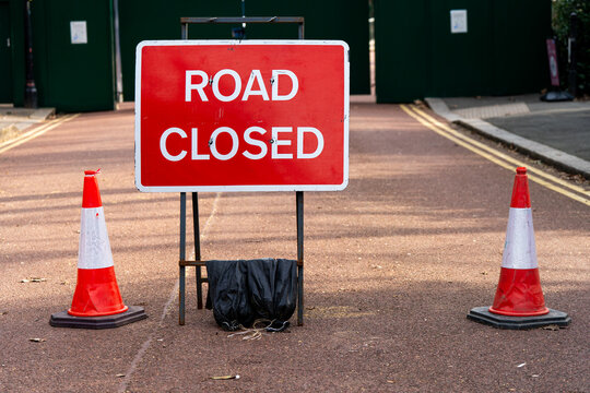 A road closed sign with traffic cones