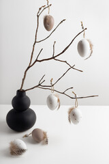 Easter composition with modern vase and decorative eggs hanging on the twigs. Easter natural background.