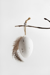 Easter composition in natural colours  with decorative egg hanging on a twig. Easter background and wallpaper.