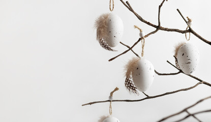Easter composition in natural colours  with decorative eggs hanging on twigs. Easter background and wallpaper, copy space for your text.