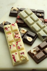 Delicious chocolate bars with different flavors on light table, closeup