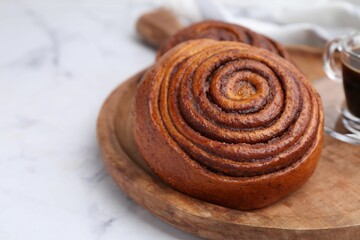 Delicious cinnamon roll on white marble table, closeup. Space for text