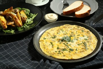 Tasty brunch. Delicious omelette and fried potatoes served on black textured table
