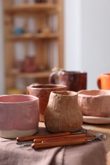 Set of different crafting tools and pottery on shelf indoors