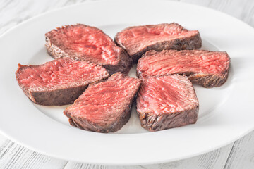 Perfectly sliced medium-rare fillet mignon steak served on a white plate